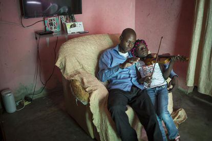 La joven estudiante de la escuela de música Kaposoka, Juelma Ferra Bernardo, toca su violín junto a la atenta mirada de su padre, en su casa del barrio de Samba, uno de los más populares en Luanda.