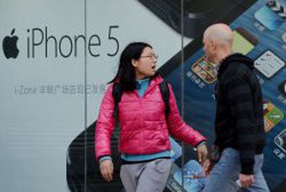 Una pareja pasea delante de una tienda de Apple en China donde se promociona el iPhone 5.