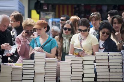 Assistents a la fira de Sant Jordi miren llibres.