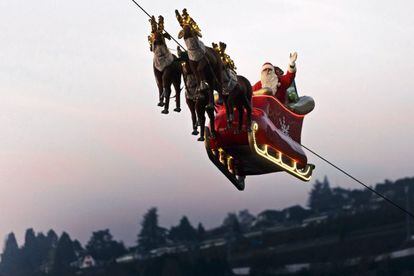 Un hombre disfrazado de Papá Noel saluda a la gente desde su trineo dirigido por renos sobre el Lago Lemán ante los alpes suizos y franceses, durante la puesta de sol de la inauguración de la vigésima edición del Mercado Navideño en Montreux, Suiza.