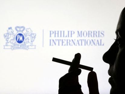 Una mujer fuma delante del logo de Philip Morris
