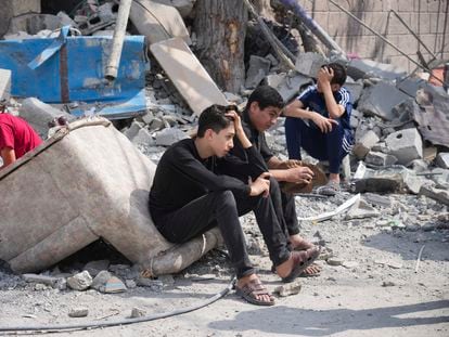 Varios jóvenes palestinos, sentados en las ruinas de un edificio bombardeado en el campo de refugiados de Nuseirat, en la franja de Gaza.