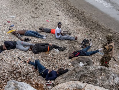 Un soldado custodia a varios jóvenes inmigrantes, algunos de ellos heridos, en la playa del Tarajal, en la frontera de Ceuta.