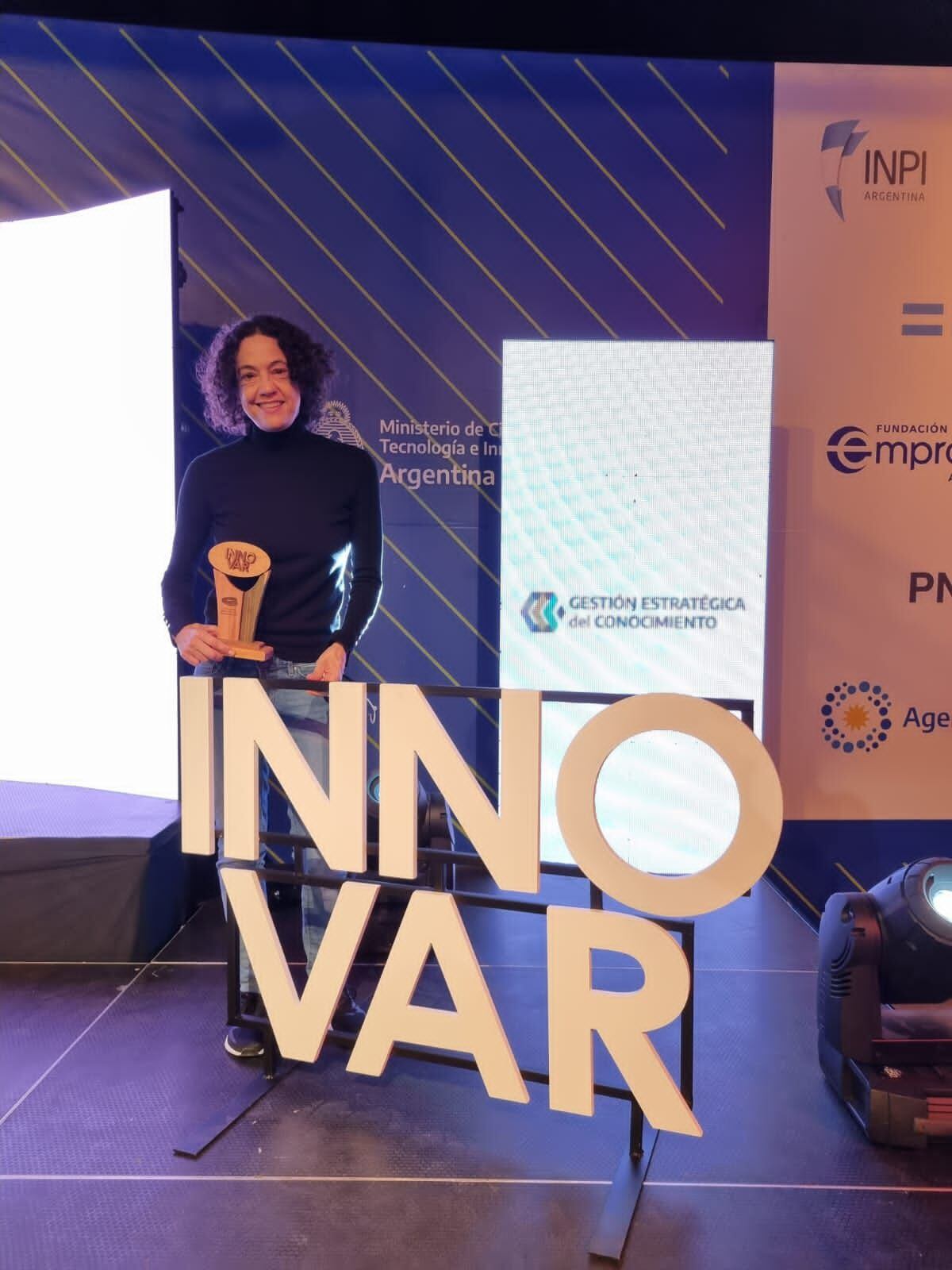 Lucía Famá sostiene la estatuilla del concurso Innovar 2022, por la elaboración de sistemas nanocompuestos activos para barbijos.