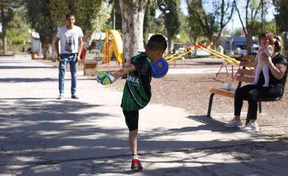 Un niño juega con su padre a la pelota en la plaza de Añelo.