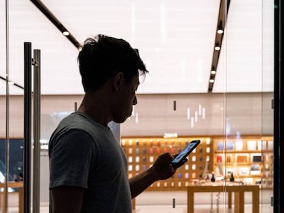 Un hombre revisa su teléfono frente a una tienda de Apple en Singapur