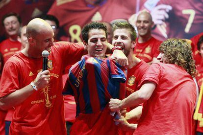 Reina, Piqué y Puyol ponen la camiseta del Barcelona a Cesc, jugador del Arsenal.