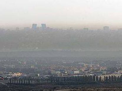 Vista aérea con las torres de la Ciudad deportiva (a la izquierda) y el magma de la contaminación abrazando a Madrid.