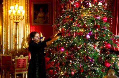 Personal de la Royal Collection Trust decorando el árbol navideño en el que, este año, destacan entre los tradicionales adornos rojos y dorados, varios en color púrpura, el preferido de Isabel II.