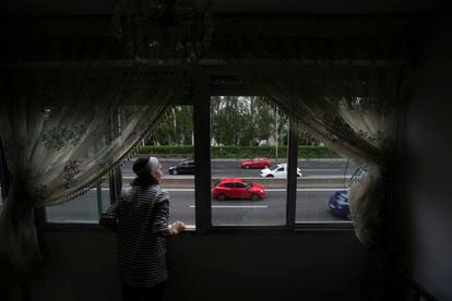 Una mujer observa el tráfico desde su casa en el barrio de Batán de Madrid.