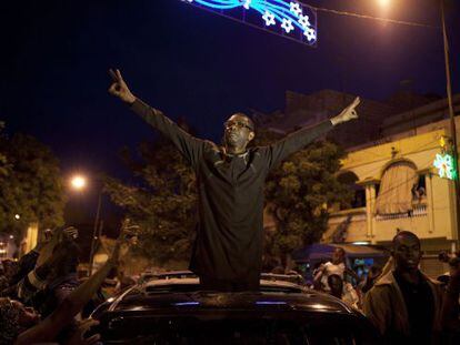 Youssou N&#039;Dour hace el signo de la victoria frente a manifestantes opositores anoche, en Dakar (Senegal).