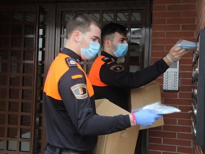 Dos voluntarios de Protección Civil, durante el reparto de mascarillas este jueves en Torrejón de Ardoz, Madrid.