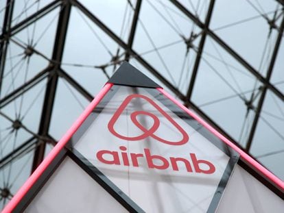 El logo de Airbnb al lado de la pirámide del museo Louvre de París, Francia. 