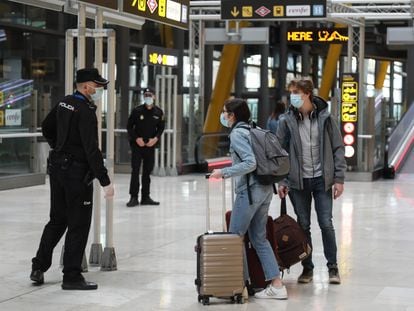 Dos viajeros y dos agentes, en el aeropuerto de Barajas el martes.