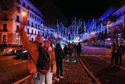 Una pareja se hace una foto con el alumbrado de la Calle Alcalá. 