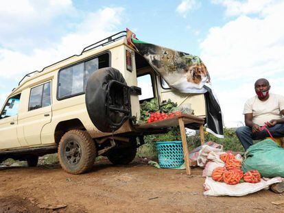 El guía de safari keniano Michael Kimani empaqueta zanahorias en bolsas junto a su coche, reconvertido en una frutería ambulante. Desde que la pandemia le dejó sin trabajo, esta es su nueva manera de ganarse la vida.    