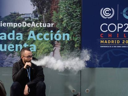 Un hombre fuma un cigarrillo electrónico en la entrada de la Cumbre del Clima que se celebra en Madrid. 