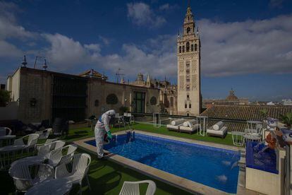 Un trabajador desinfecta la piscina con vistas a la Giralda del hotel Doña María, en Sevilla.