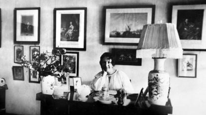 La escritora danesa posa para la foto apoyada en una mesa de retratos y un jarrón con flores.