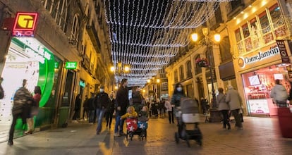 Varios viandantes, en la calle Alfonso I de Zaragoza, adornada con el alumbrado navideño.