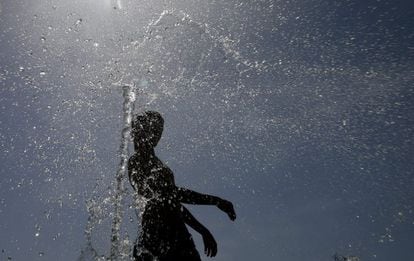 Un joven intenta aliviar el calor refrescándose en una de las fuentes del parque Juan Carlos I en Madrid.