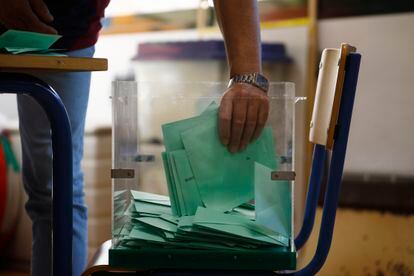 Una de las personas responsables recoge los votos de una urna para proceder al recuento de votos en un colegio de Córdoba.