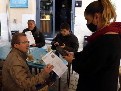 Una camarera pide certificado a los clientes en una mesa en la terraza de un bar en Málaga.