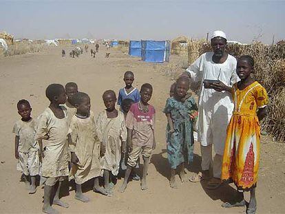 El jeque tribal Ahmed Abdell Alí escucha la radio con sus hijos en el campo de desplazados de Shangil Tobaya.