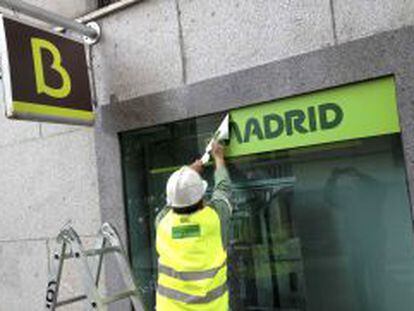 Un operario cambia carteles en una oficina de Bankia. 