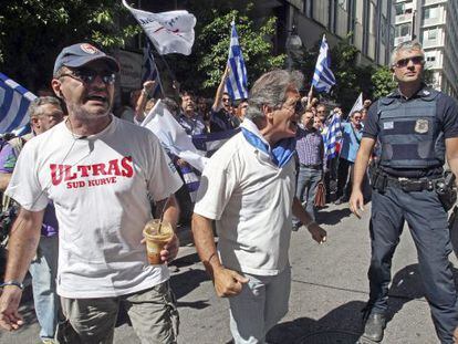 Griegos se manifiestan mientras esperan a los representantes de la troika frente al ministerio griego de Finanzas en Atenas.