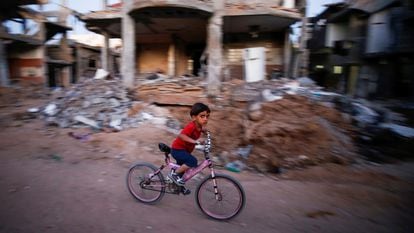 Un niño pasa en bicicleta ante una casa destruida por los bombardeos, el domingo en Gaza.