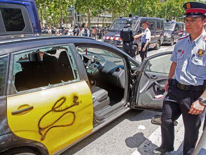 Un taxi destrozado durante la protesta de ayer del sector en la Diagonal de Barcelona. 