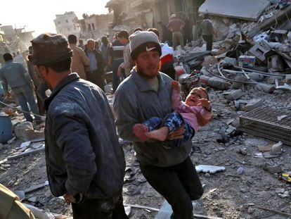 Un hombre sostiene en sus brazos a un niño tras los bombardeos aéreos en un mercado en Atareb, en el norte de Siria, este lunes.