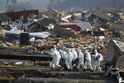 Un grupo de policías japoneses transportan un cuerpo durante la operación de recuperación de las víctimas del terremoto y posterior tsunami, en Namie, Prefectura de Fukushima, el 11 de marzo de 2011.