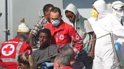 Miembros de la Cruz Roja asisten a rescatados en el naufragio a su llegada al puerto de Palermo.