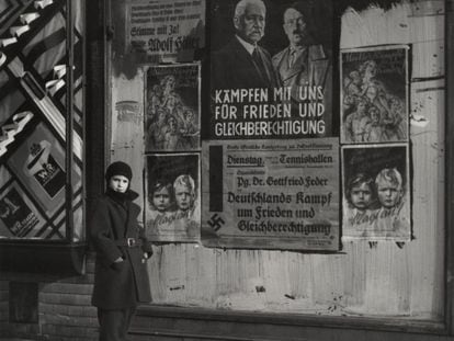 Mara, hija de Vishniac, posa delante de un cartel electoral de Hindenburg y Hitler que lee: "El mariscal y el cabo: lucha con nosotros por la paz y la igualdad de derechos,"Wilmersdorf, Berlín, 1933