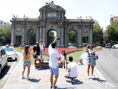 Varios turistas se fotografían ante la puerta de Alcalá, en el centro de Madrid