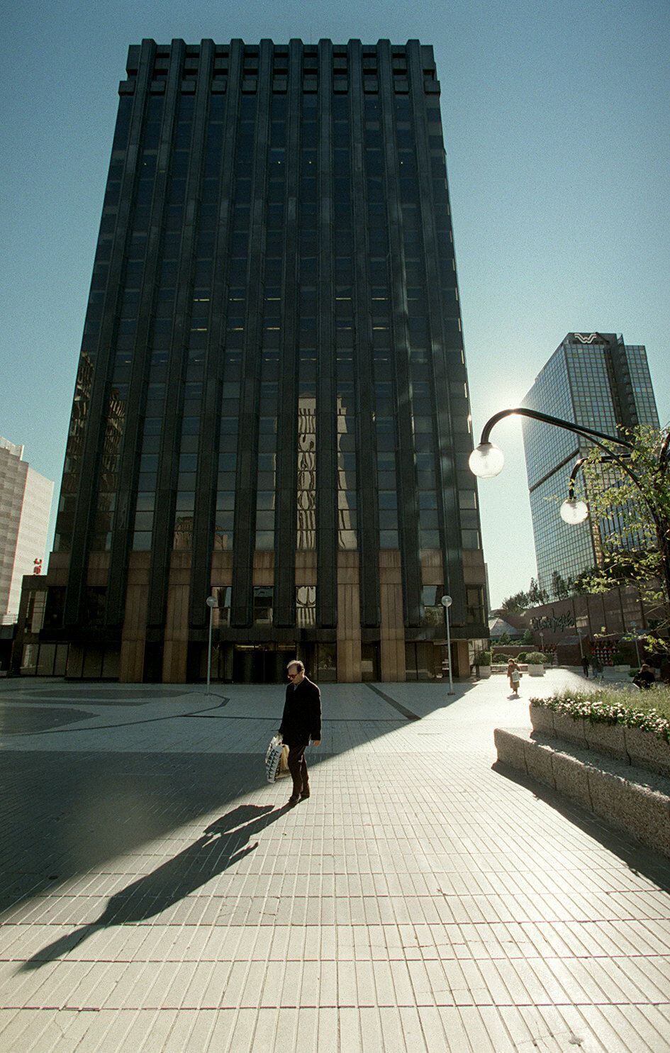 Un hombre pasea ante el edificio del Banco Santander en el cumplejo AZCA. Al fondo, la Torre Windsor.