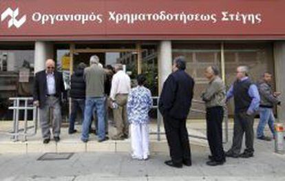 Varias personas esperan ante una sucursal de la Corporaci&oacute;n Financiera de la Vivienda de Chipre.