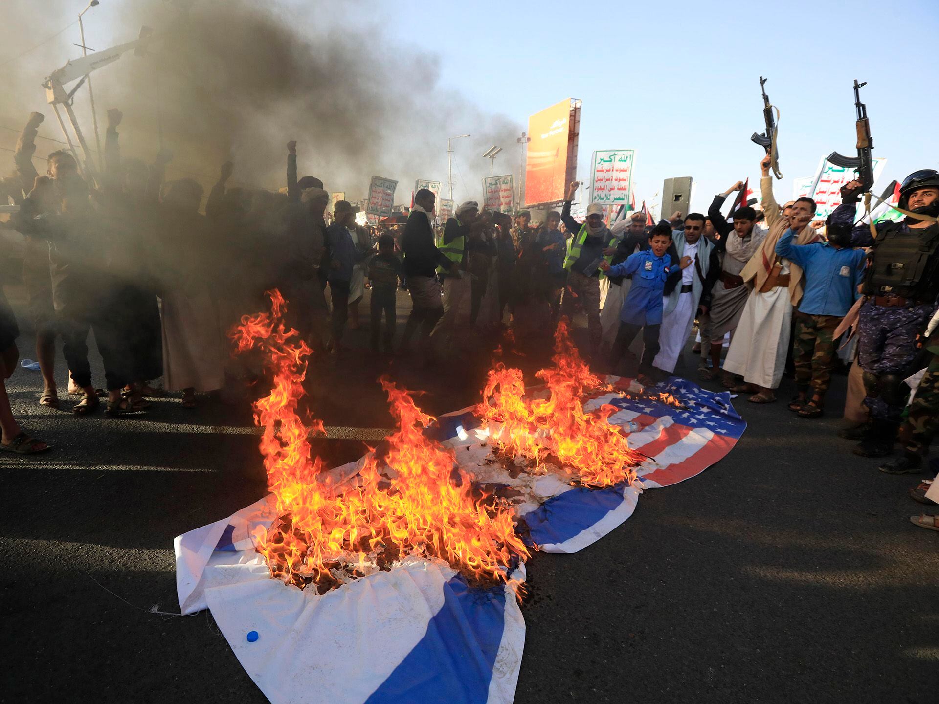 Un grupo de personas quema una bandera estadounidense y otra israelí este viernes en Saná.