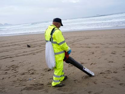 Un operario retira 'pellets', este miércoles en la playa asturiana de Salinas.