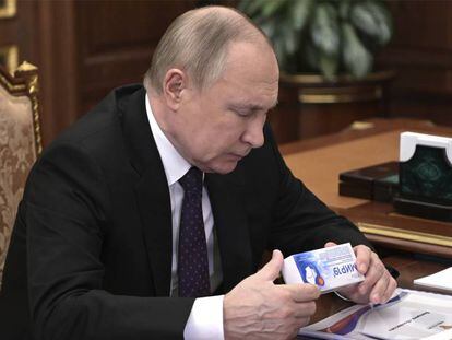 El presidente de Rusia, Vladimir Putin, mirando una caja de un medicamento en una conferencia el 15 de marzo