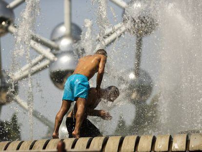 Dos hombres se refrescan en una fuente de Bruselas, cerca del Atomium, este miércoles.