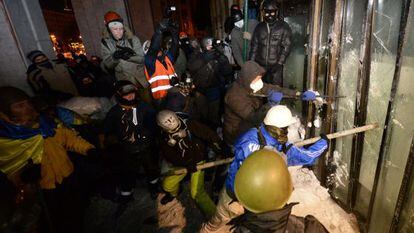Manifestantes contra el Gobierno asaltan la Casa Ucrania, en el centro de Kiev, donde se hab&iacute;an refugiado los antidisturbios. 