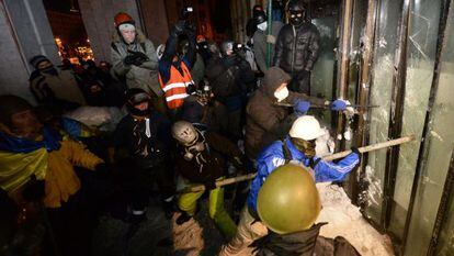 Manifestantes contra el Gobierno asaltan la Casa Ucrania, en el centro de Kiev, donde se habían refugiado los antidisturbios.