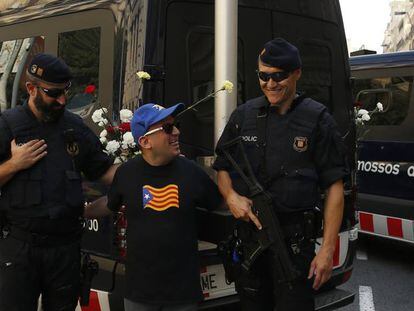 Un hombre con la camiseta con la estelada posa para una foto con dos mossos