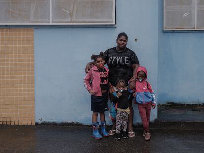 Priscila Santos con tres de sus hijas junto a un agujero de bala en el muro de una escuela del Complexo da Maré, en Río de Janeiro.