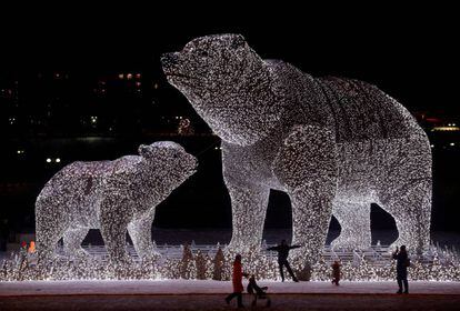 Varias personas se reúnen cerca de una instalación iluminada que representa a dos osos polares antes de las fiestas de Año Nuevo y Navidad en un parque de Moscú, Rusia.