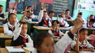Los estudiantes de una clase de lengua tibetana levantan la mano para responder una pregunta en el Colegio Experimental de educación primaria de Lhasa, capital de la región autónoma de Tíbet, en junio de 2009.  