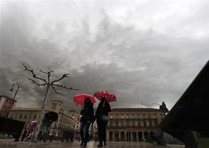 Dos personas se protegen del agua con un paraguas este sábado en la plaza del Castillo de Pamplona.